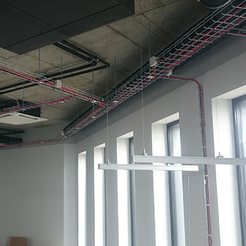 Trasy kablowe wraz z ułożonymi przewodami w przestrzeni biurowej